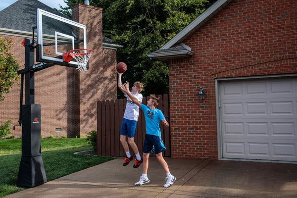 athletes playing on in ground basketball hoop