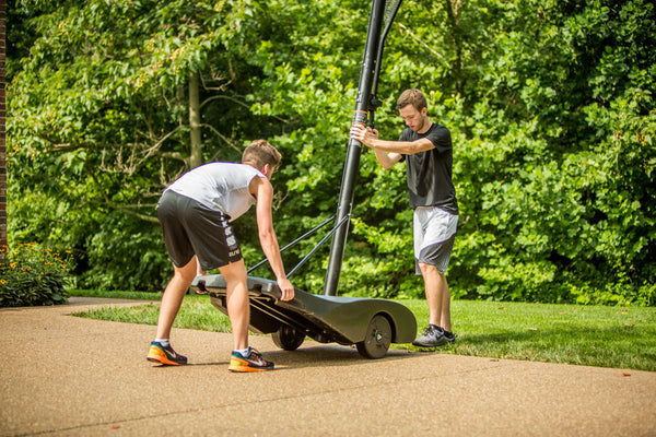 athletes moving a portable basketball hoop