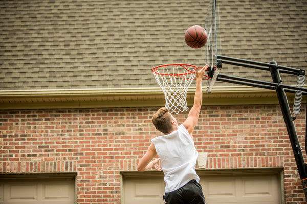 athlete playing on a portable basketball hoop - in ground vs portable basketball hoops - learn more about in ground vs portable