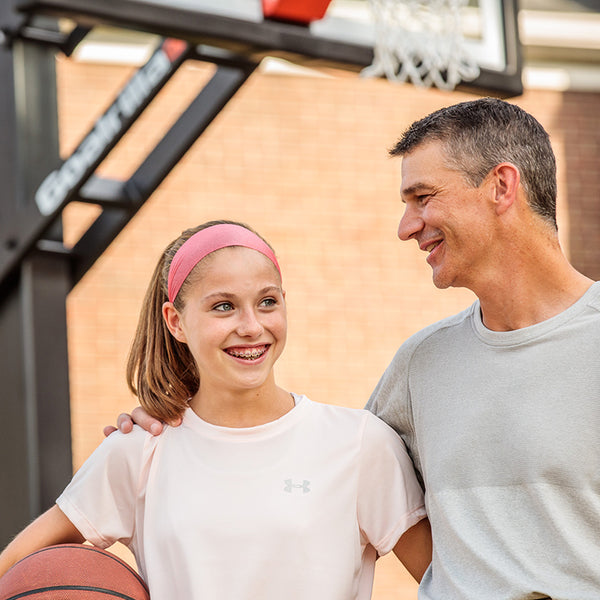 dad and daughter in front of an outdoor basketball hoop