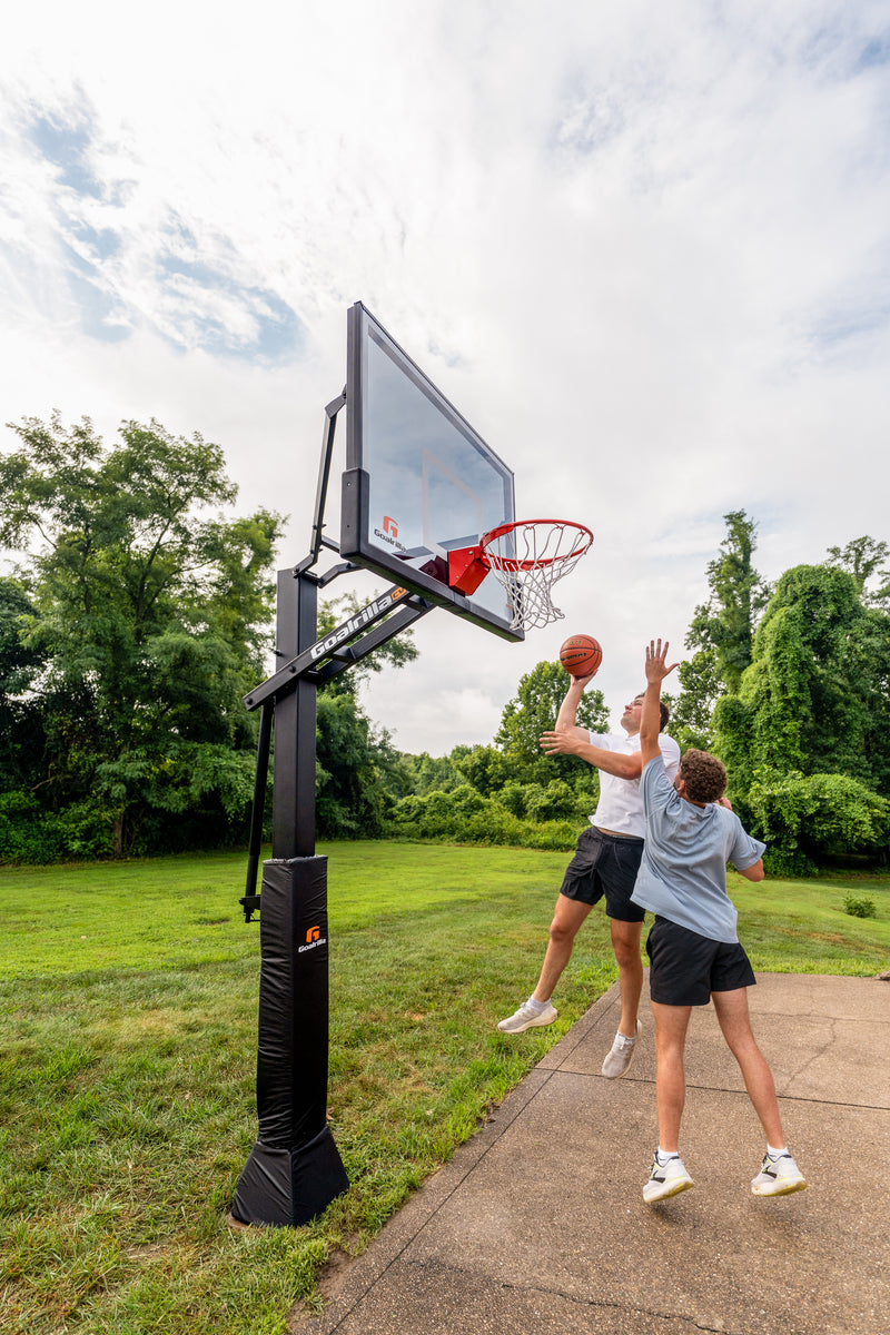 Two people playing basketball outdoors with a Goalrilla CV60T basketball hoop.